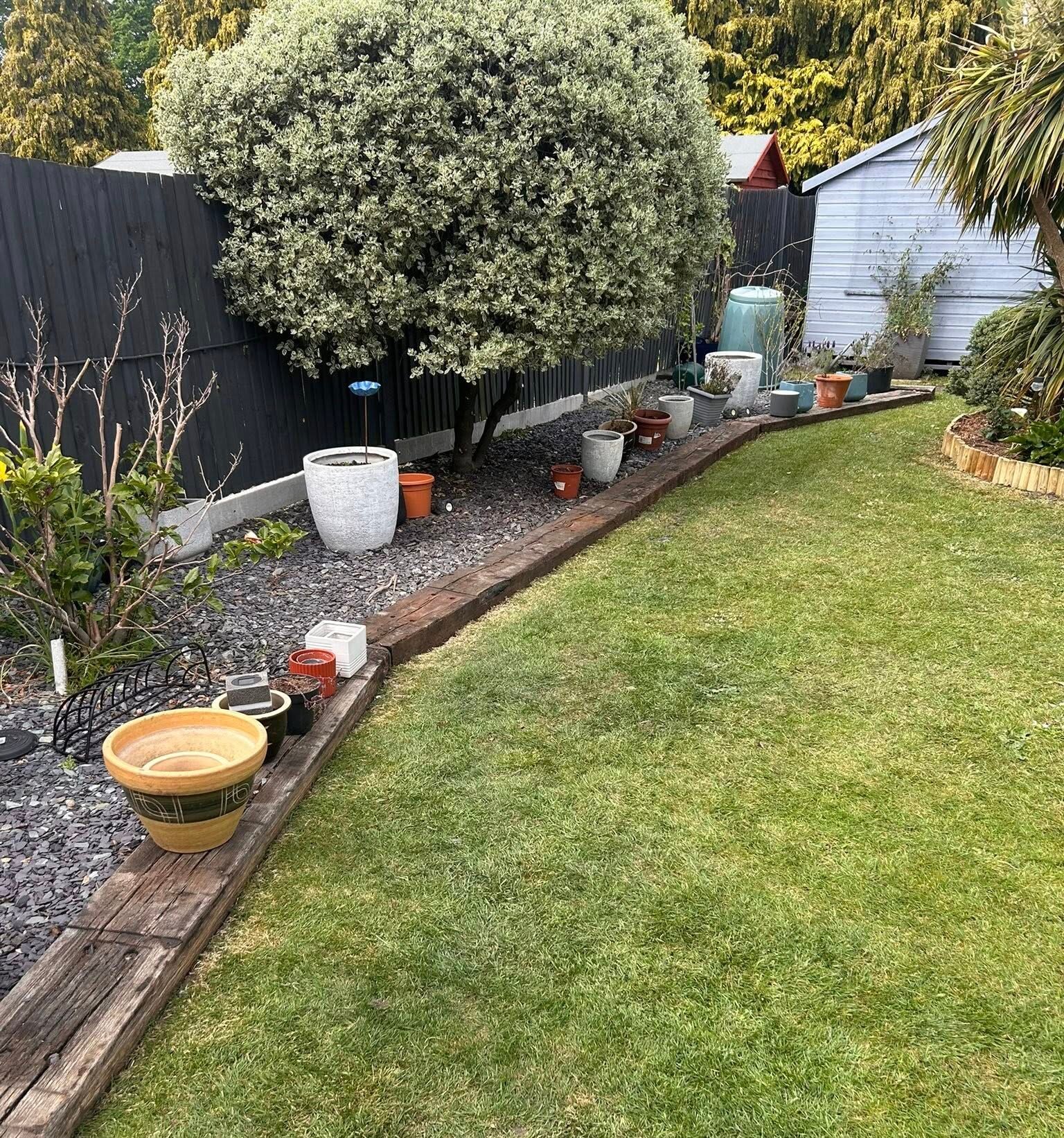 the image shows a good looking garden with planters and trim round the side of the border. The grass is neatly cut and the trees are clean and tidy.